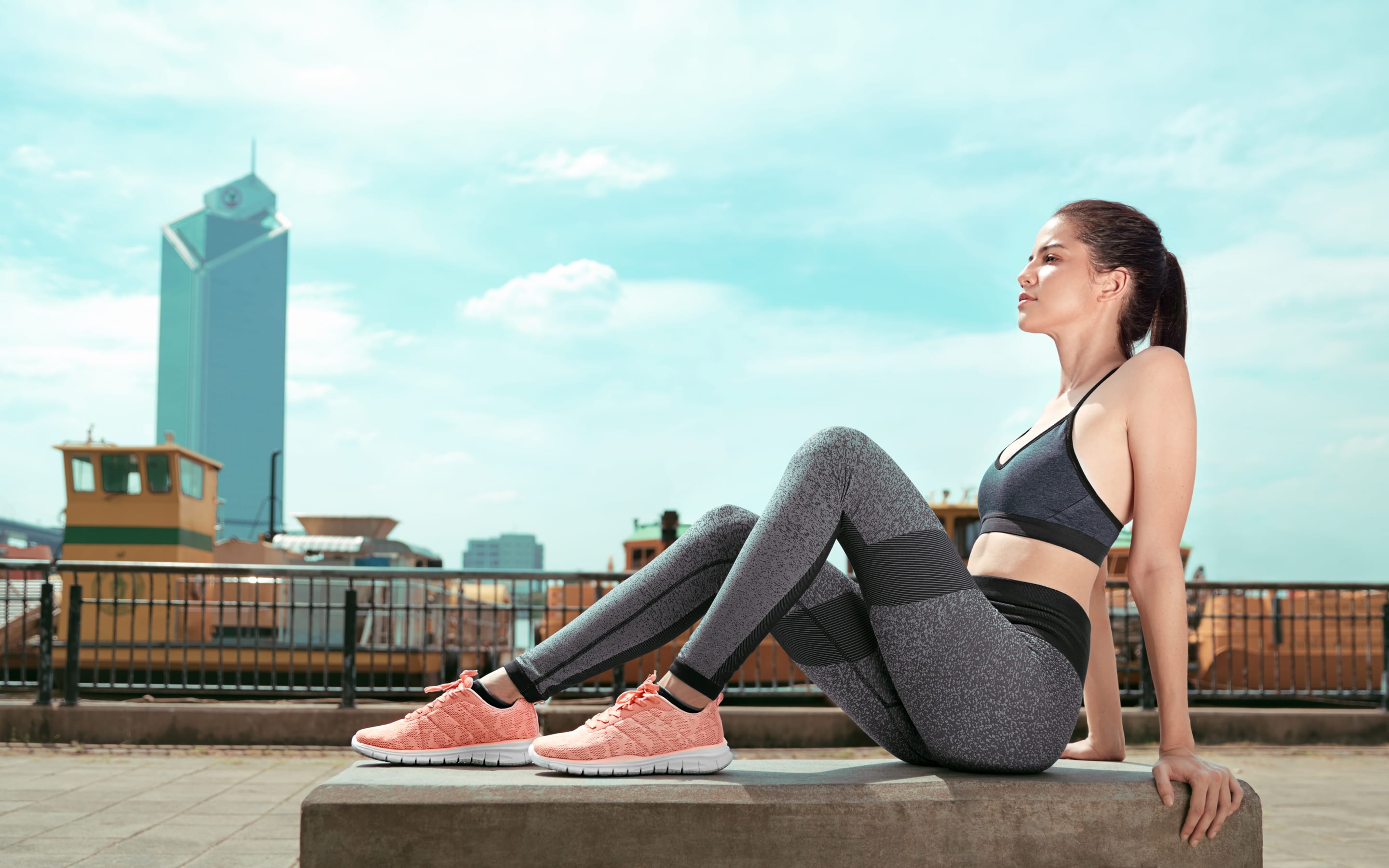 The pink pair off duty: a model on a concrete bench against the harbour
